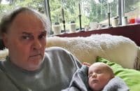 Old, Unkempt, Confused Man Holding Baby On Couch