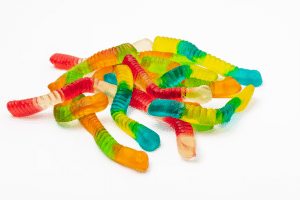 A small pile of colorful gummy worms against a white background.